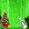 Christmas tree decorated with lights and gifts in front of a bright green curtain with string lights.