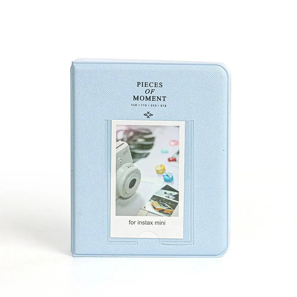 Light blue square album cover with silver text and a window displaying instant camera photos.