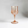 A clear, textured, rose gold colored plastic wine glass with a stem and foot.