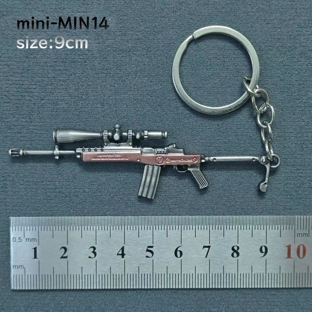 A miniature alloy gun model keychain with a realistic finish is shown next to a ruler.