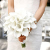 A person holds a bouquet of white calla lily stems for bouquets and decor.