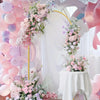 Elegant gold metal wedding arch stand with a pink and white floral backdrop featuring balloons and drapery