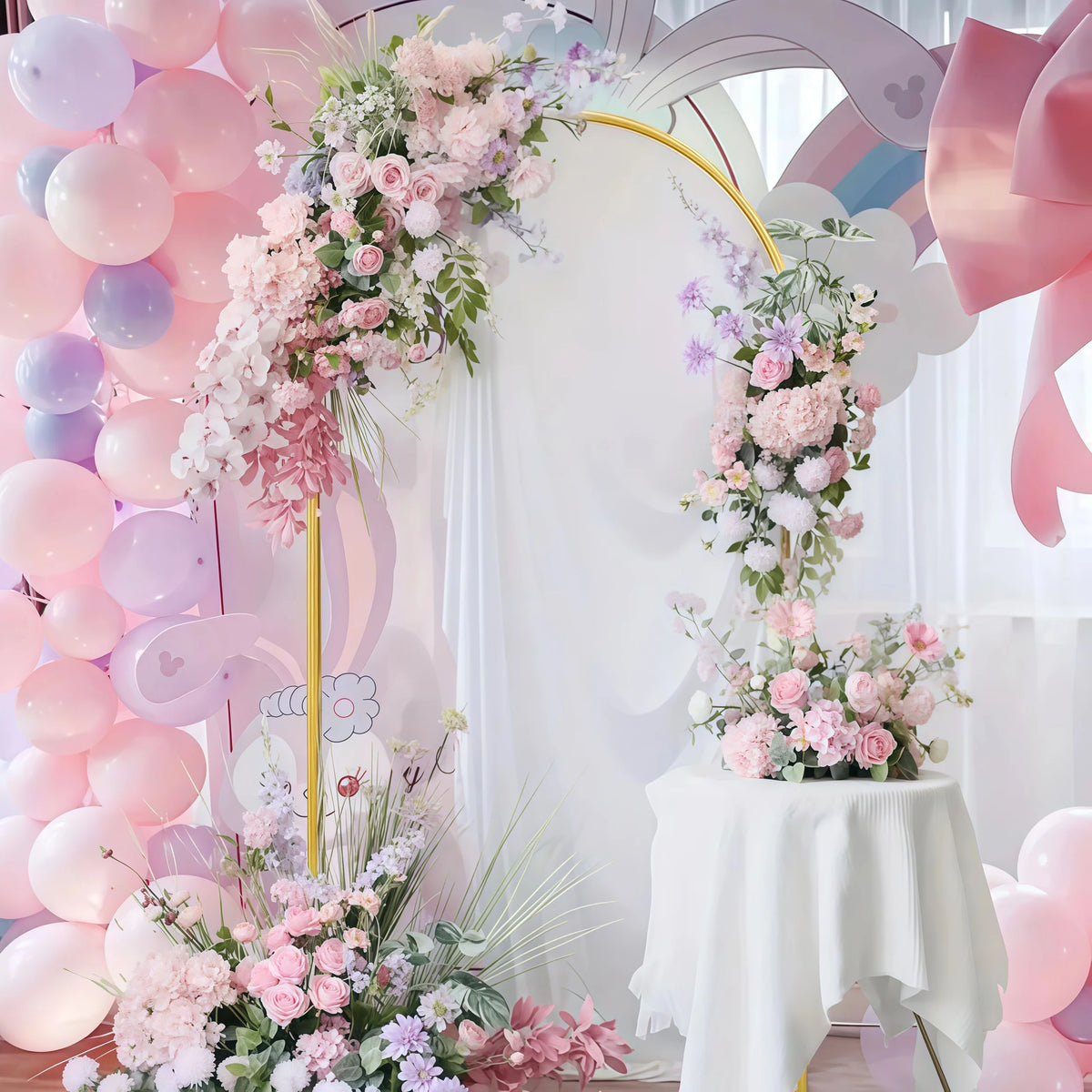 Elegant gold metal wedding arch stand with a pink and white floral backdrop featuring balloons and drapery