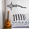 Black line sculpture of a shark swimming across a white wall above a bed.
