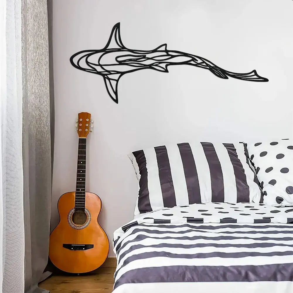 Black line sculpture of a shark swimming across a white wall above a bed.
