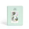 A light mint green album cover titled Pieces of Moment for instant cameras with a clear window displaying photos.