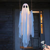 A white glowing ghost decoration hangs on a door, displayed against a stone wall and wooden door.