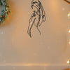 A black line art silhouette of a girl with long hair against a light wall, decorated with soft bokeh lights and falling snowf