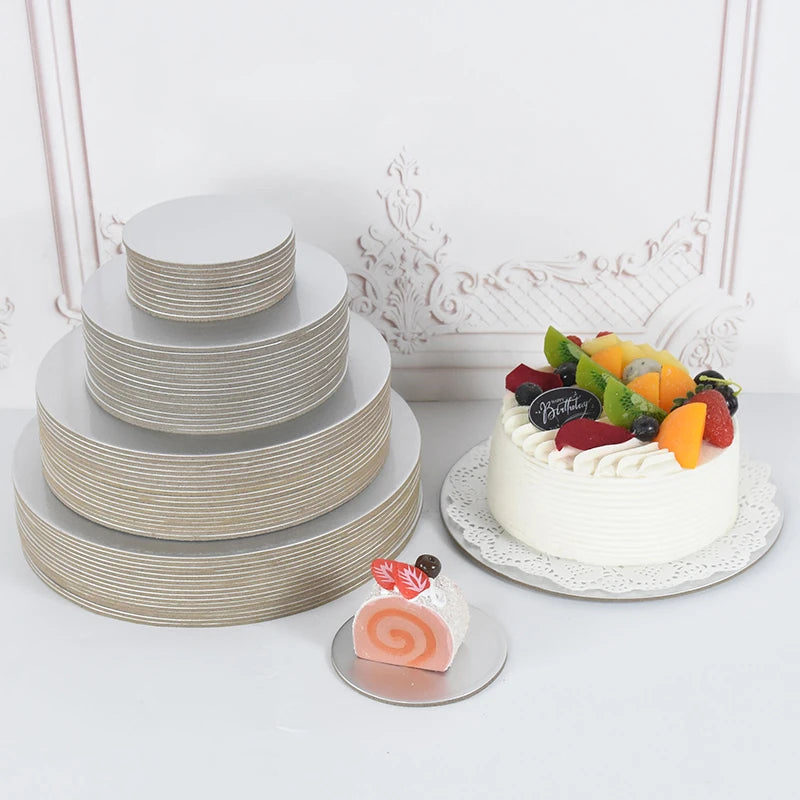 A tiered white cake board with silver stripes and a small white cake decorated with fresh fruit.