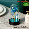A glass dome containing an artificial blue rose flower with yellow stems, displayed on a black base.