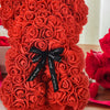 Künstlicher Rosen-Teddybär aus leuchtend orange-roten Rosen, mit schwarzer Schleife gebunden.