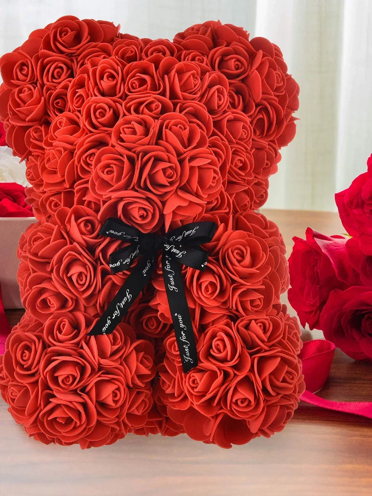Künstlicher Rosen-Teddybär aus leuchtend orange-roten Rosen, mit schwarzer Schleife gebunden.