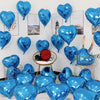 A collection of blue heart-shaped foil balloons displayed against a white wall with framed pictures.