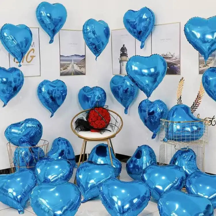 A collection of blue heart-shaped foil balloons displayed against a white wall with framed pictures.