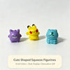 A set of three cute shaped squeeze figurines in purple, yellow, and blue on a white surface.
