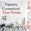 A white tapestry featuring a custom picture design, displayed on a wall with a potted plant and furniture.