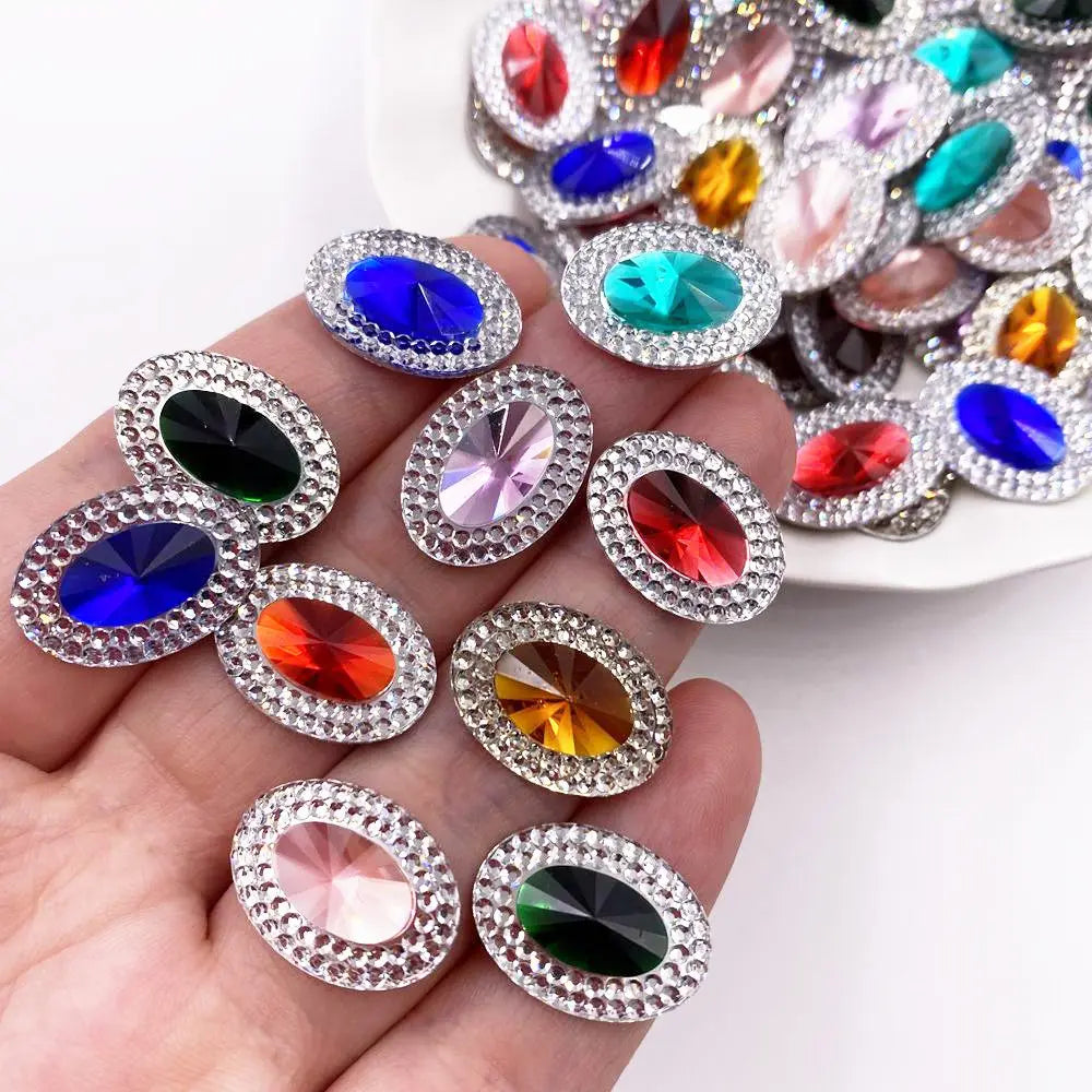 A collection of colorful gemstone flatback rhinestones in various shades of blue, red, green, and pink are displayed on a han