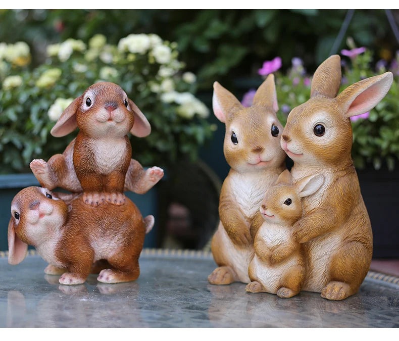 A hand-painted resin garden statue featuring a mother rabbit and her baby, sitting on a stone surface.