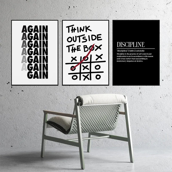 Three black and white motivational quote prints on a gray wall above a light wooden chair.