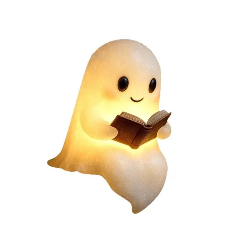 A cute ghost night light shaped like a glowing figure reading an open book.