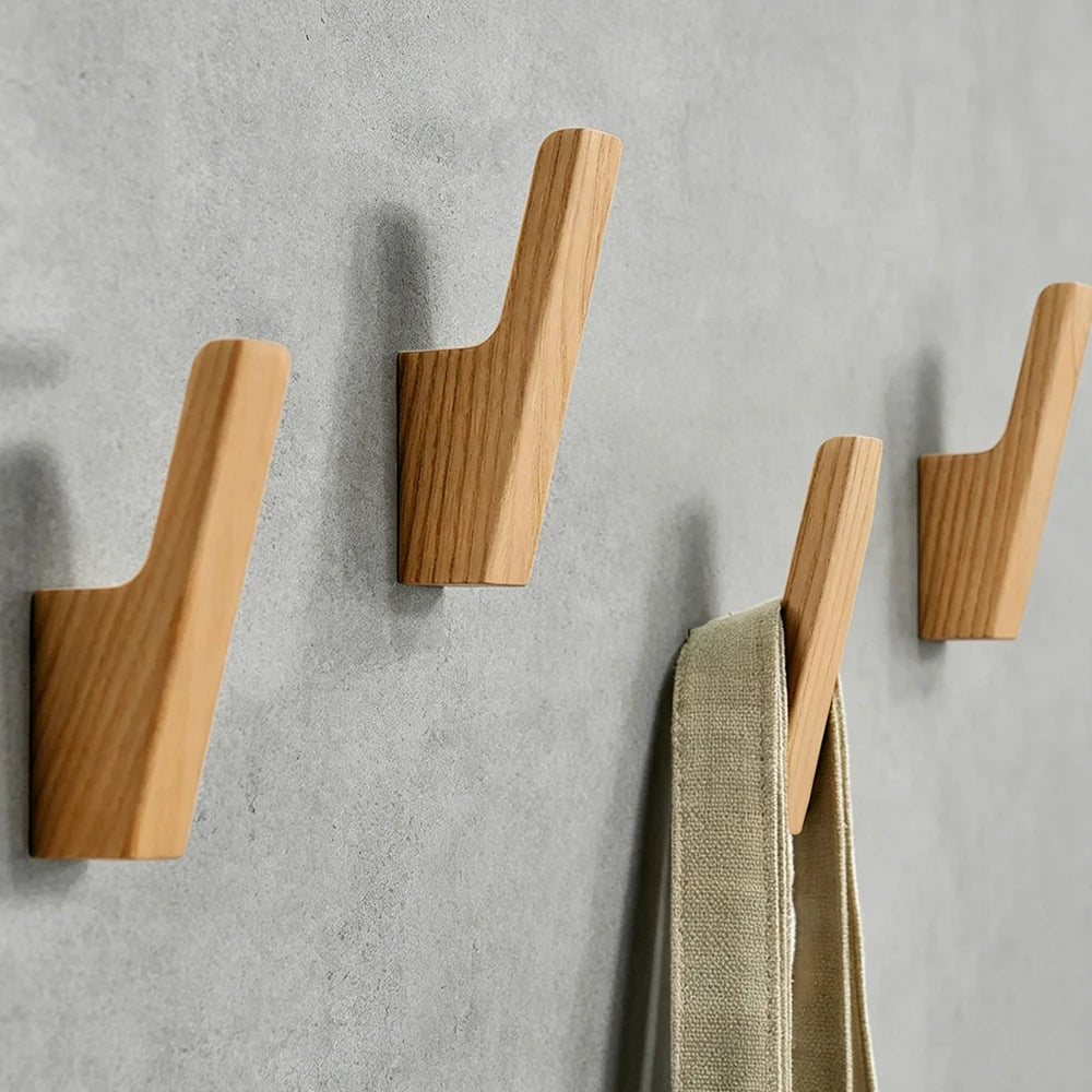 Set natürliche Holz-Wandhaken zum Aufhängen von Mänteln, Taschen und Handtüchern an einer grauen Wand.
