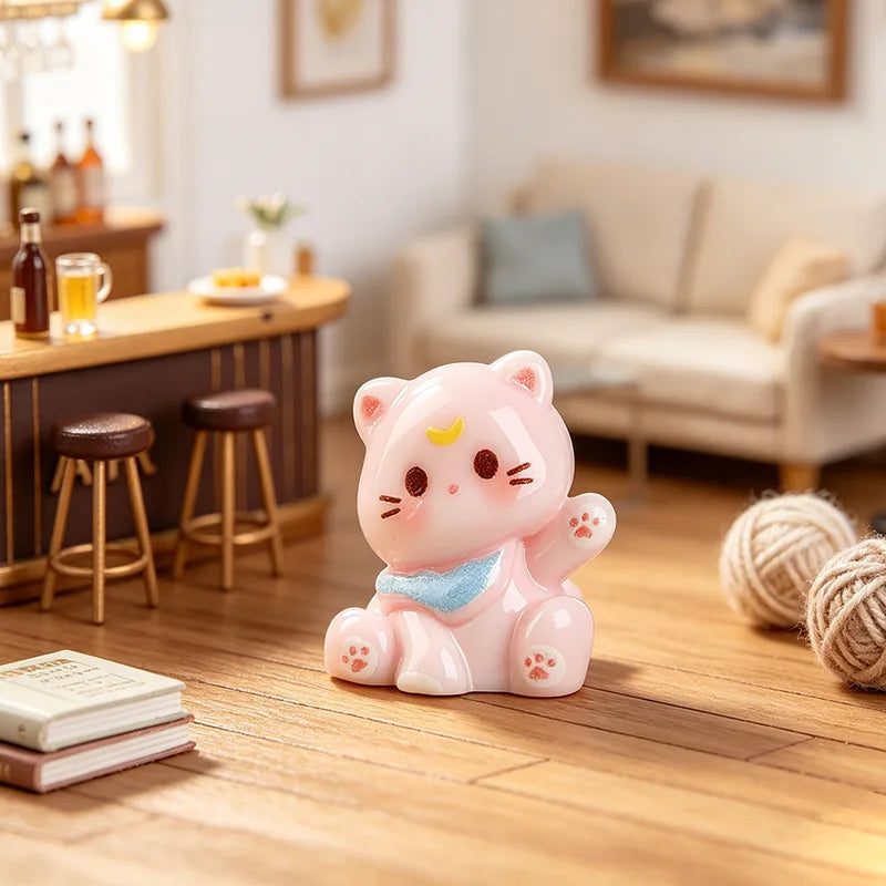 A pink resin cat keychain sitting on a wooden floor next to a stack of books.