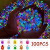 A hand holds a pile of glow-in-the-dark resin turtle figurines in various bright colors against a colorful background.