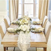 Una rústica mesa de madera puesta para una comida con arreglos florales blancos y detalles de encaje.