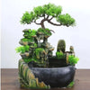A resin waterfall desktop fountain featuring a mossy rock structure and green foliage.