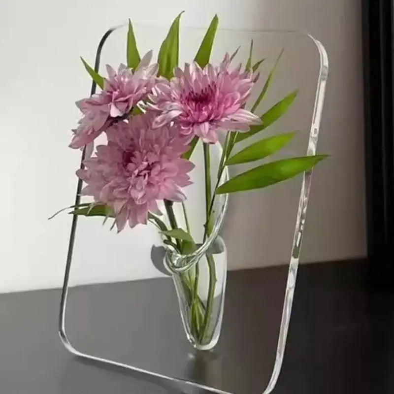 A clear acrylic frame holds a vase with pink dahlia flowers.