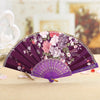 Purple lace hand fan with floral embroidery displayed on a light surface.