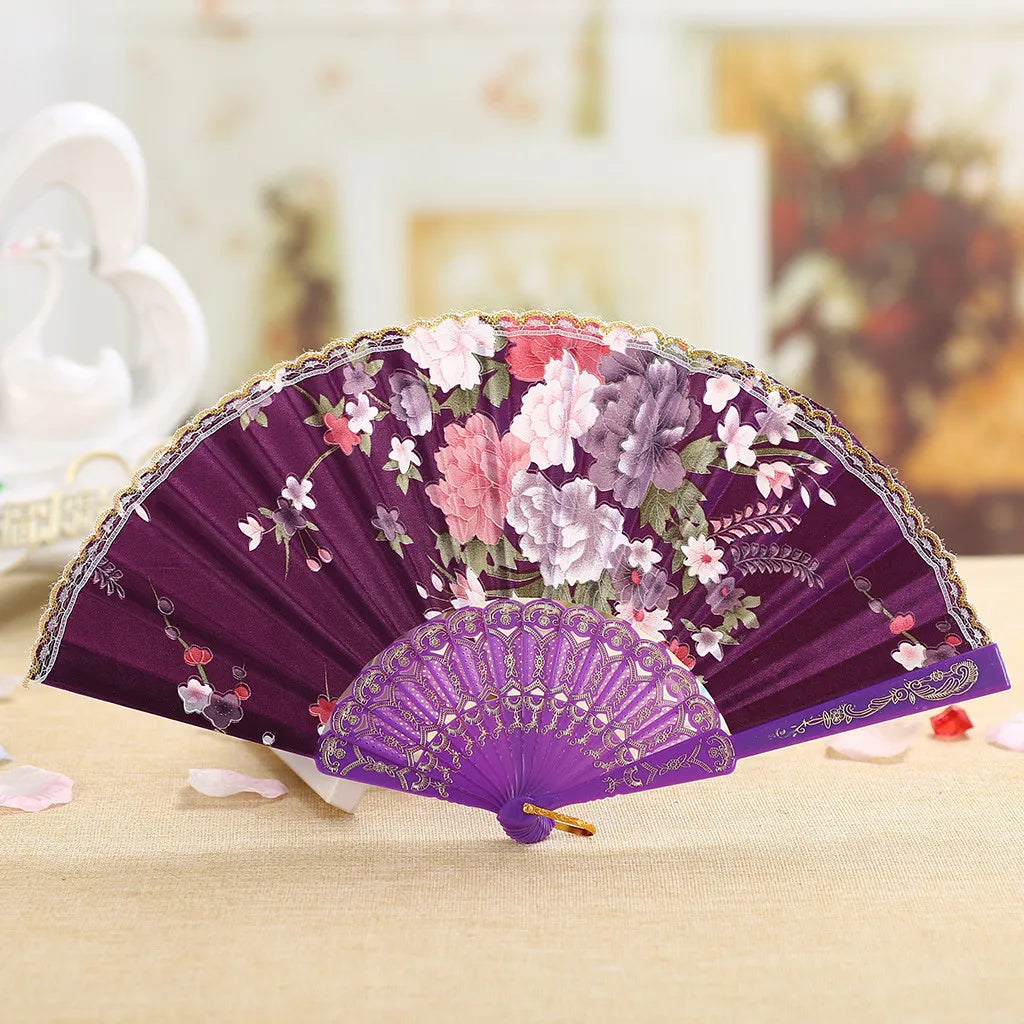 Purple lace hand fan with floral embroidery displayed on a light surface.
