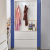 A white cabinet with blue decorative trim displays several draped scarves and a framed picture.
