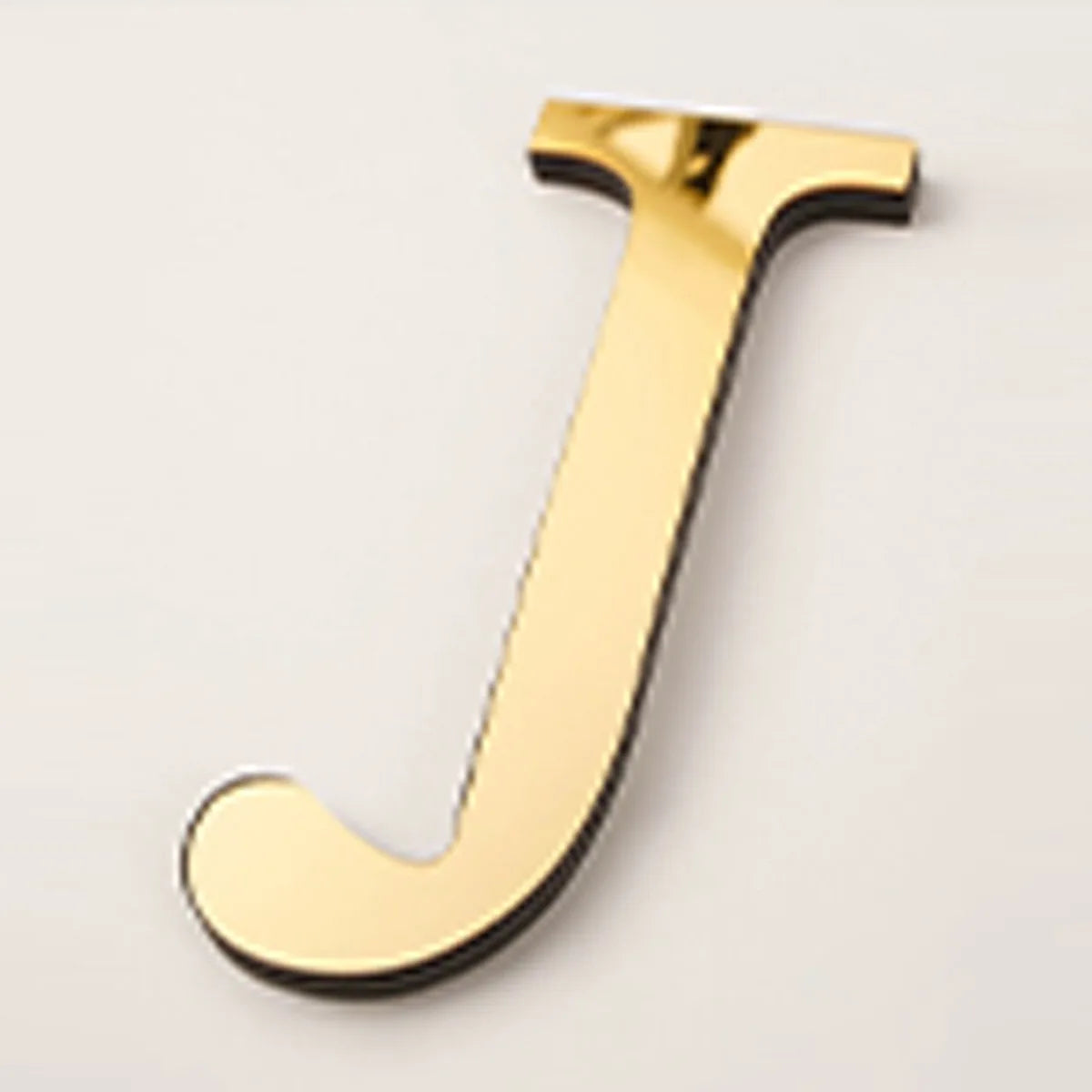 A shiny gold acrylic letter J wall sticker for decorative purposes.