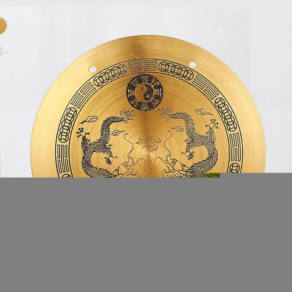 A round brass Feng Shui Zen table gong featuring dragon and Taiji symbols engraved on its surface.