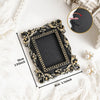 A black vintage baroque resin hanging photo frame with gold accents displayed on a white surface.