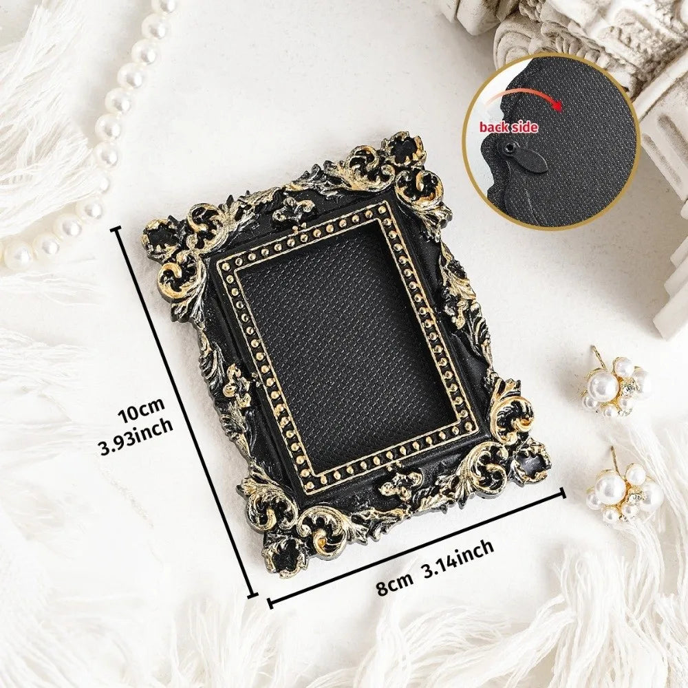A black vintage baroque resin hanging photo frame with gold accents displayed on a white surface.