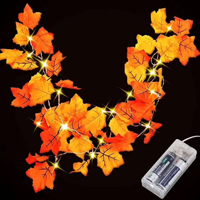 Autumn leaf garland with orange and yellow leaves illuminated by warm LED lights for fall decoration