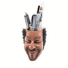 A terracotta artistic face planter holding several thin glass tubes or tools.