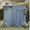 A light blue chiffon backdrop curtain decorated with floral accents for a wedding or event.