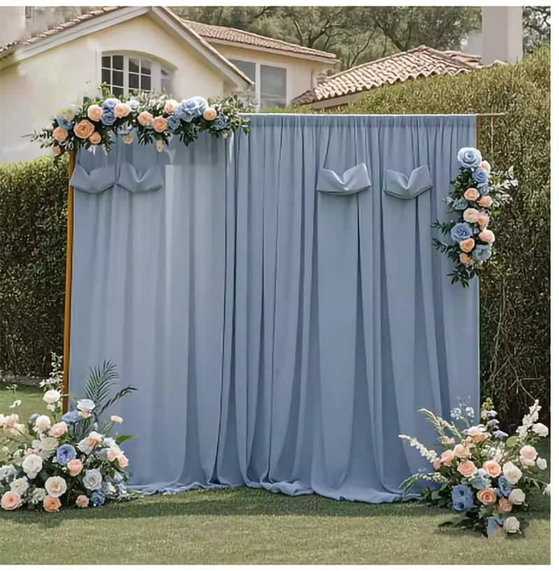 A light blue chiffon backdrop curtain decorated with floral accents for a wedding or event.