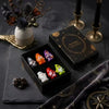 A collection of Halloween witch mini dwarf resin figurines in various colors displayed on a dark surface.