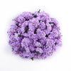 Un bouquet dense de petites fleurs d'hydrangea artificielles violettes.