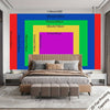 A large wall tapestry featuring vibrant vertical stripes of red, blue, green, and purple framing a bed.