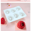 White silicone raspberry mousse molds and a fresh raspberry fruit displayed on pink surfaces.