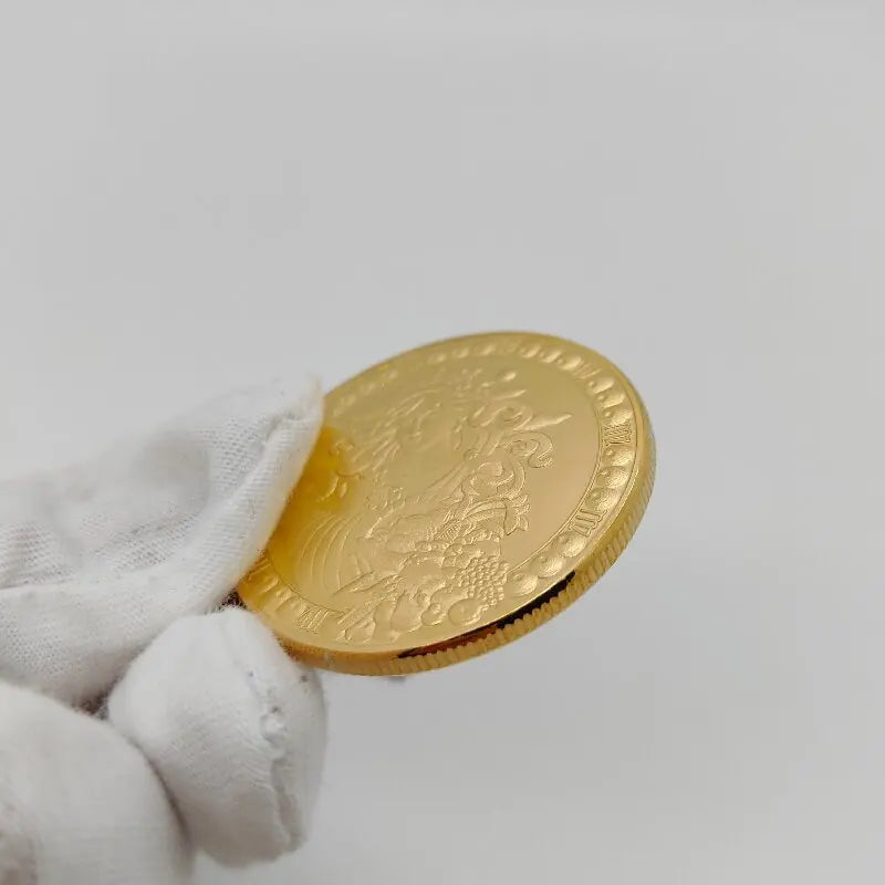 A hand holds a gold commemorative iron coin with an embossed design against a white background.