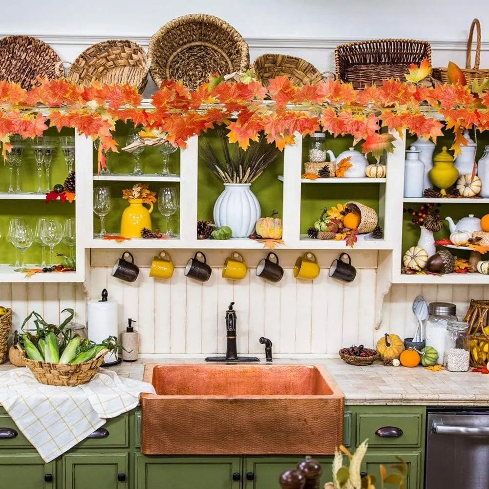 Artificial maple leaf garland hanging vine displayed on a wooden shelf with various decorative items.