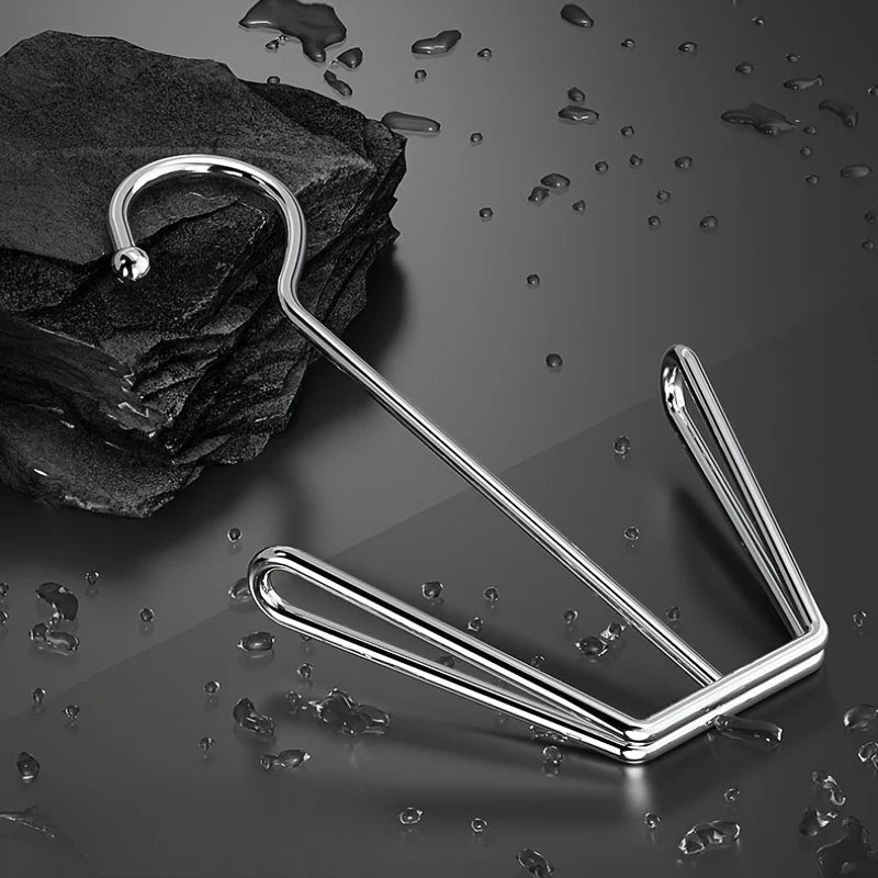 A stainless steel hanging shoe organizer with a double hook resting on a dark surface.