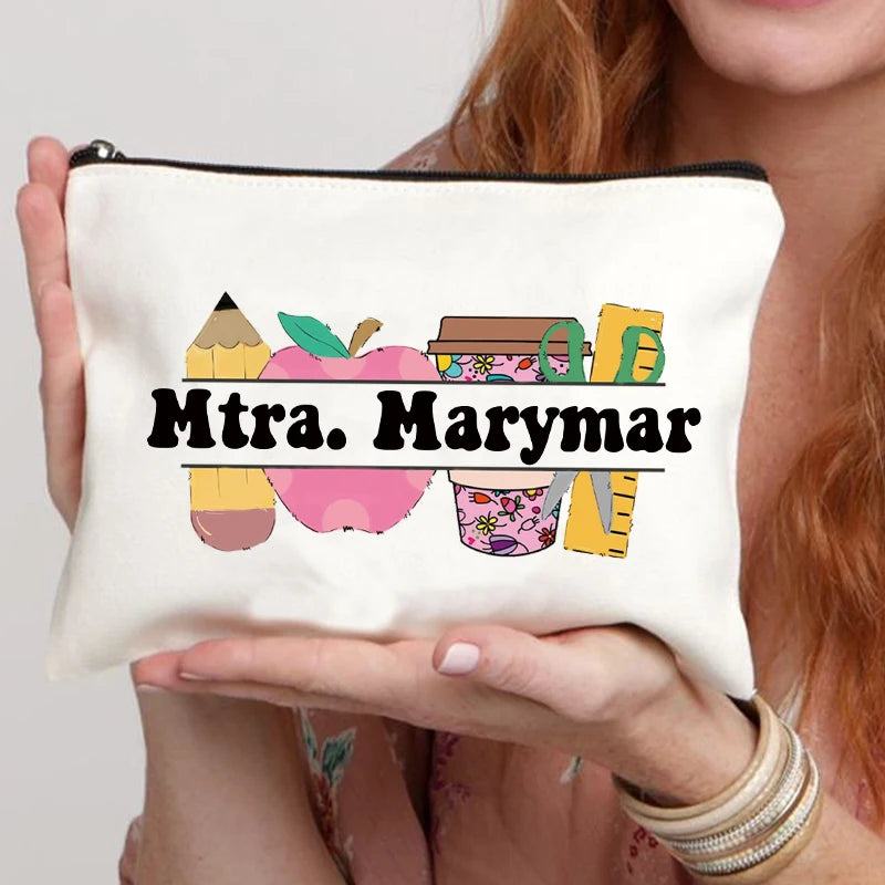 A white canvas makeup bag with a black zipper features the text Mtra. Marymar and colorful fruit illustrations.