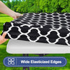 Black and white geometric patterned waterproof elastic fitted tablecloth being held over a white table.